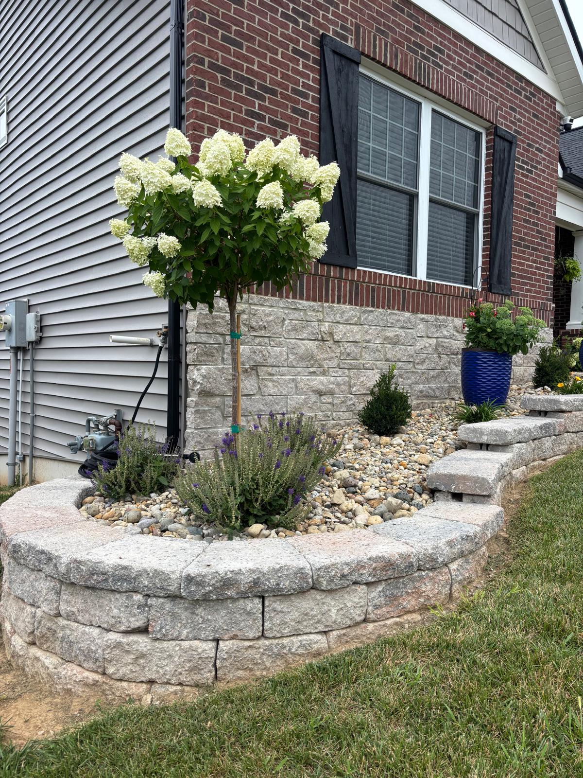 Raised landscape bed with decorative stone and flowering plants