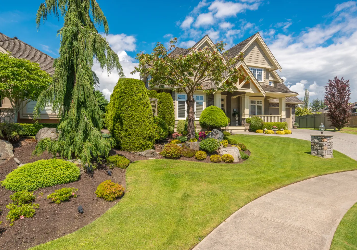 Beautiful home with manicured lawn, landscaped shrubs, and mature trees